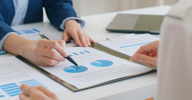 Man pointing at financial charts with pen.