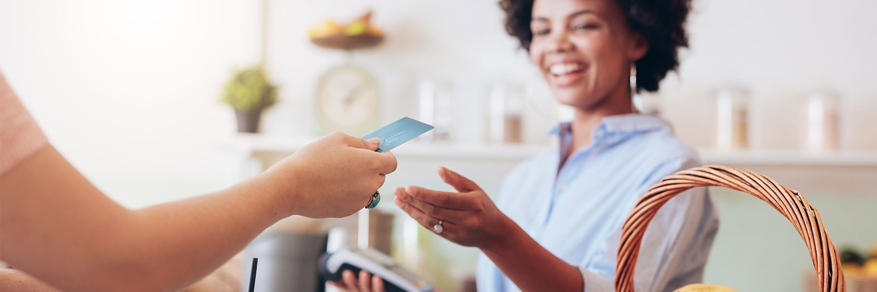 Shot of a female juice bar owner taking payment from customer with debit card.